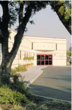 small photo of little white building behind a shady tree, this is the cancer treatment center