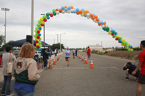 runners finishing rotary cancer run/walk, running through big balloon arch