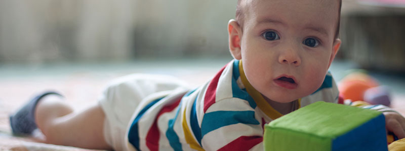 Baby raising head while lying on tummy showing what tummy time for babies looks like.